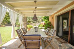 een veranda met een tafel en stoelen op een patio bij Villa Anna in Ágios Ioánnis