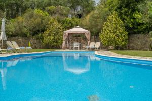 een blauw zwembad met een prieel en stoelen bij Villa Anna in Ágios Ioánnis