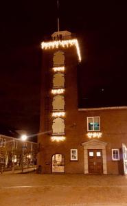 un edificio con una torre con luces. en De Oude Kazerne Torenkamer, en Kaatsheuvel