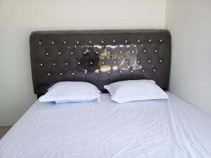 a bed with a black headboard and two white pillows at Brand new vacation house- Private gated community in Banda Aceh