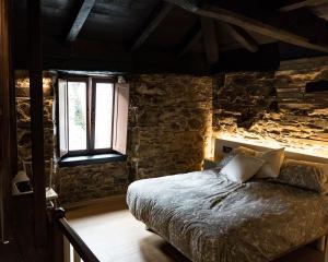 um quarto com uma cama e uma parede de pedra em Casa Nastasia em A Pontenova