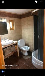 a bathroom with a toilet and a sink and a tub at Roztoczańskie Chatki in Kaczórki