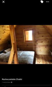a log cabin with two beds and a window at Roztoczańskie Chatki in Kaczórki