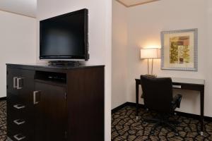 Holiday Inn Express & Suites Tacoma South - Lakewood, an IHG Hotel في ليكود: غرفة في الفندق مع مكتب وتلفزيون وكرسي