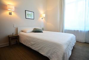 a bedroom with a white bed with a window at La Citadine in Neufchâteau