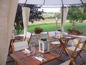 a table and chairs under an umbrella on a patio at Chambres d'Hôtes Domaine de Beunes in Pailloles