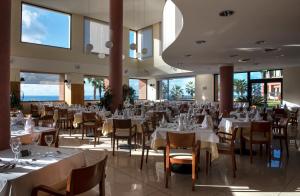 een restaurant met witte tafels, stoelen en ramen bij Monte Mar Palace Hotel in Ponta Delgada