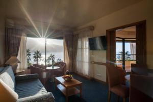 een woonkamer met een bank, een tafel en een raam bij Monte Mar Palace Hotel in Ponta Delgada