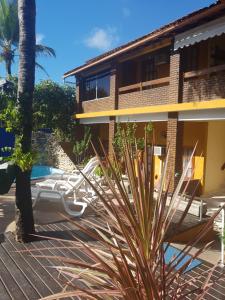 a resort with a palm tree and chairs next to a building at Pousada A Flor da Terra in Arraial d'Ajuda