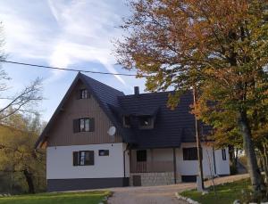 a brown and white house with a black roof at Plitvice Streaming in Prijeboj