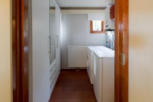 una pequeña cocina con armarios blancos y un pasillo en Drents Genieten - Kraaiheide met privé jacuzzi, en Erm