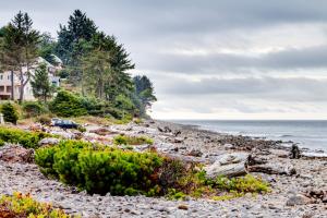 a rocky beach with a house and the ocean at Spacious Seaside Home with an Ocean View in Seaside