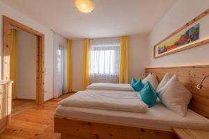a bedroom with a large bed with blue pillows at Garni Appartements Almrausch in Burgusio