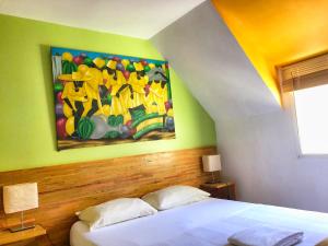 Schlafzimmer mit einem Bett mit Wandgemälde in der Unterkunft Residence Deshroses in Deshaies