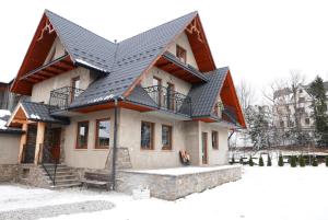 una casa con techo negro en la nieve en Pietrasówka, en Jurgów