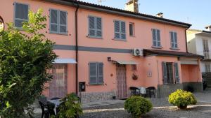 a pink house with blue shutters on it at Marinella Guest House in Cornale