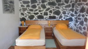 two beds in a room with a rock wall at Casa da Alícia in Feiteira
