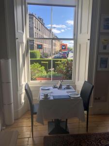 una mesa con sillas en una habitación con una ventana grande en Sheridan Guest House en Edimburgo