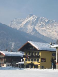 un edificio con una montaña cubierta de nieve en el fondo en Sporthotel Schönau am Königssee, en Schönau am Königssee