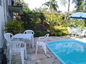a patio with a table and chairs next to a pool at Hotel Pousada Rio Mar in Ubatuba