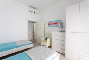 a white bedroom with a bed and a dresser at Sea View Apartment Mellieha in Mellieħa