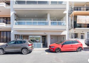 two cars parked in a parking lot in front of a building at Sea View Apartment Mellieha in Mellieħa
