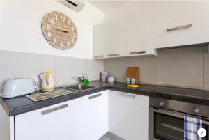 a kitchen with white cabinets and a clock on the wall at Sea View Apartment Mellieha in Mellieħa