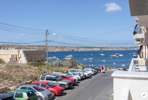 a row of cars parked on a street next to the water at Sea View Apartment Mellieha in Mellieħa