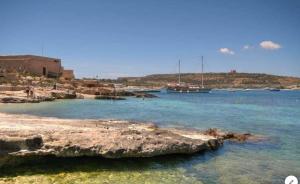two boats are docked in the water near a beach at Sea View Apartment Mellieha in Mellieħa