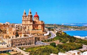 an old building on a hill next to a road at Sea View Apartment Mellieha in Mellieħa