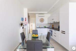a kitchen and dining room with a glass table and chairs at Sea View Apartment Mellieha in Mellieħa