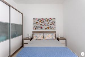 a bedroom with a blue bed and a painting on the wall at Sea View Apartment Mellieha in Mellieħa