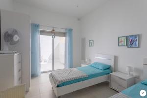 a white bedroom with a bed and a window at Sea View Apartment Mellieha in Mellieħa