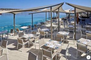 un restaurante con mesas y sillas y el océano en View Point Ghadira Melliha, en Mellieħa