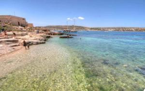 a beach with a group of people on the water at Sea View Apartment Mellieha in Mellieħa