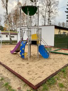 a playground with a slide in the sand at Monti Domki całoroczne in Mierzyn