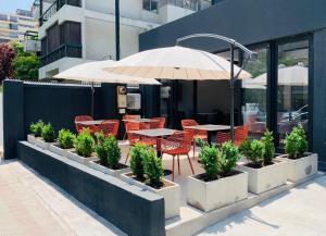 un patio con mesas, sillas y una sombrilla en The PopCity Hotel, en Santiago