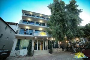 un grand bâtiment blanc avec un arbre en face dans l'établissement Hotel Diandra, à Eforie Nord