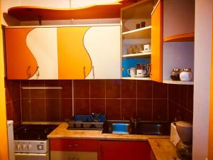 a kitchen with orange and white cabinets and a sink at Nexus Holiday in Miercurea-Ciuc