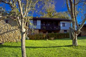 a house in a field with trees in front of it at Casa Rural La Retuerta in Nava