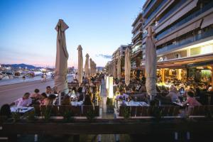 a group of people sitting at tables with umbrellas at SUNNY CENTRAL LUXURY APARTMENT in Volos