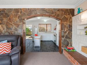 a kitchen and living room with a stone wall at Heathcote Cottage - Taupo Holiday Home in Taupo