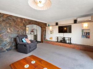 ein Wohnzimmer mit einer Steinmauer und einem Stuhl in der Unterkunft Heathcote Cottage - Taupo Holiday Home in Taupo