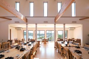 a large room with tables and chairs and windows at Shimayado Goen in Ojika