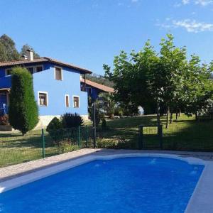 a large blue swimming pool in front of a house at Apartamentos y Habitaciones Casa Bego in Valdredo