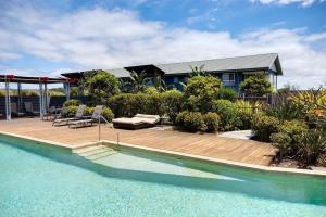 a house with a wooden deck and a swimming pool at Serenity Diamond Beach in Diamond Beach