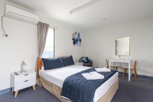 a bedroom with a bed and a table and a desk at Tin Can Bay's Sleepy Lagoon Motel in Tin Can Bay