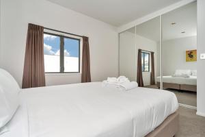 a white bedroom with a large bed and a window at QV Modern 3 Level Sunny Townhouse (640) in Auckland