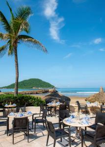 una playa con mesas, sillas y una palmera en Pueblo Bonito Mazatlan Beach Resort - All Inclusive, en Mazatlán