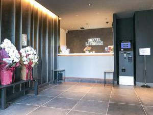 a lobby with flowers on a bench and a counter at HOTEL LiVEMAX Chiba Soga-Ekimae in Chiba